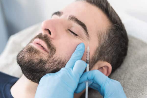 Man with dark hair and beard having having forehead botox injection