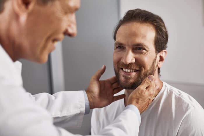 smiling man with dark hair receiving examination of lymph nodes