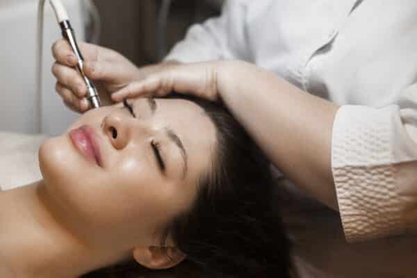 beautiful brunette woman receiving microneedling treatment