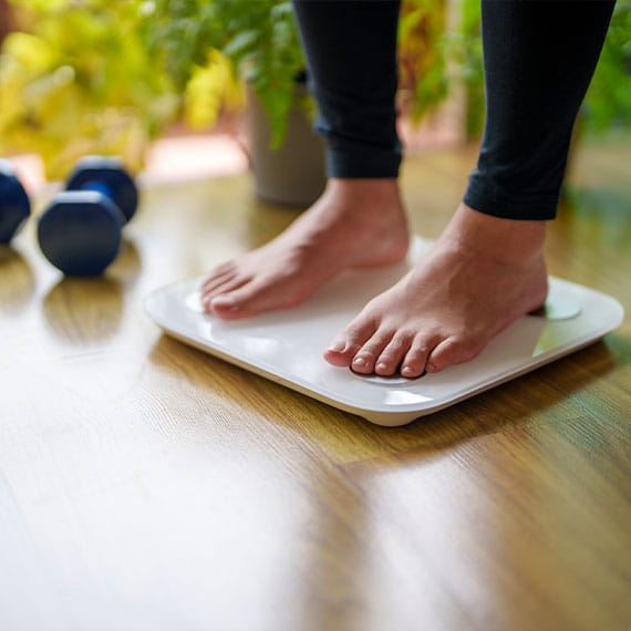 woman standing on scale before getting post weight loss surgery in Newport News, VA
