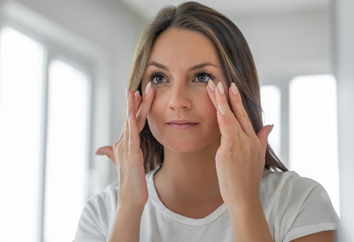 woman looking in the mirror after getting a brow lift in Newport News, VA