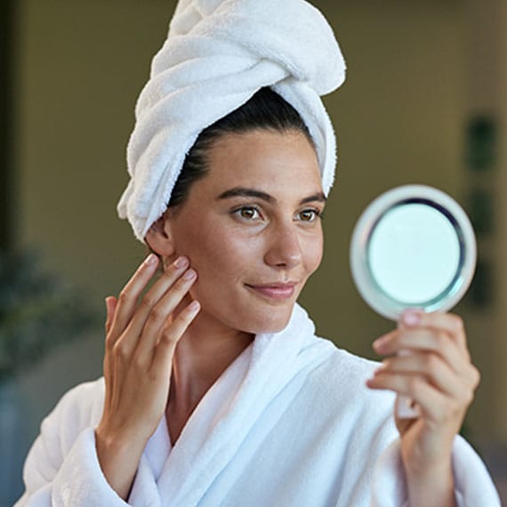 woman looking in a small mirror after getting botox in Williamsburg, VA